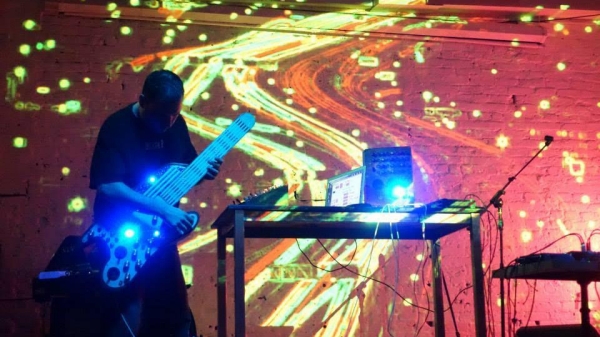 a person playing an electric guitar with a lot of swirly patterns projected on the wall