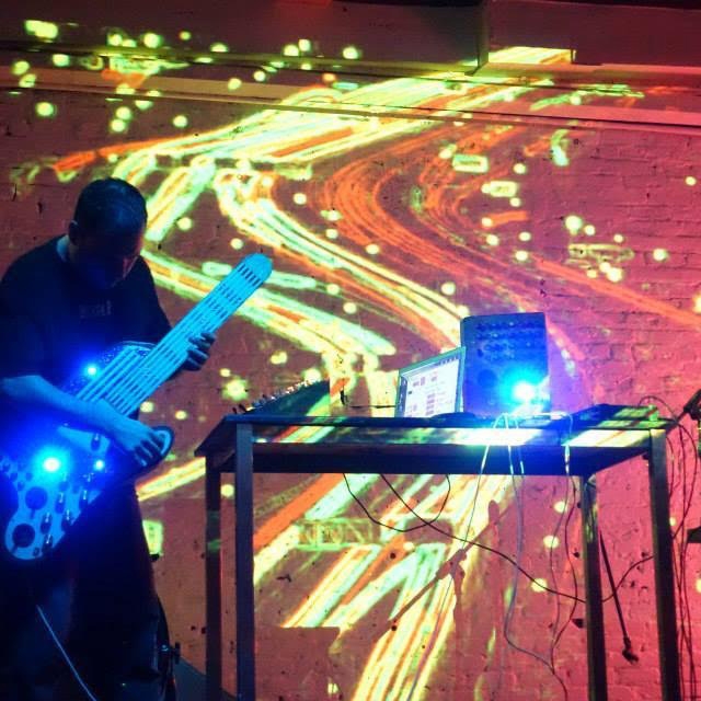 a person playing an electric guitar with a lot of swirly patterns projected on the wall