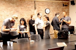 a group of people standing and talking in front of black tables