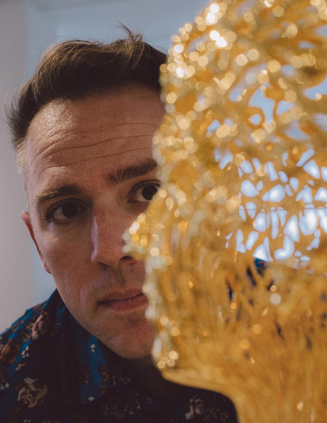 closeup of a man in the background looking at a side angle yellow sculpture of a person