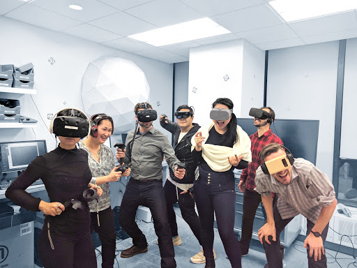 Students using VR gear and smiling at the camera