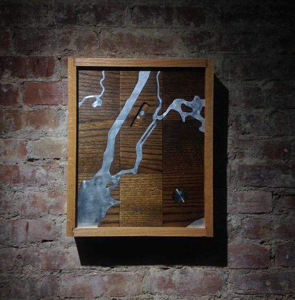 a wooden and metal framed project hanging on a brick wall