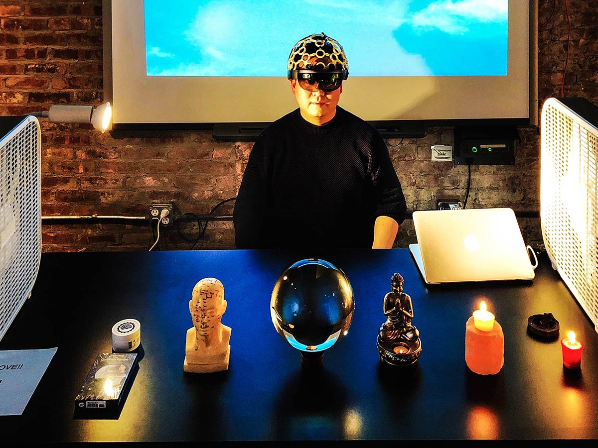 A man wearing a brain wave helmet sitting with meditative candles