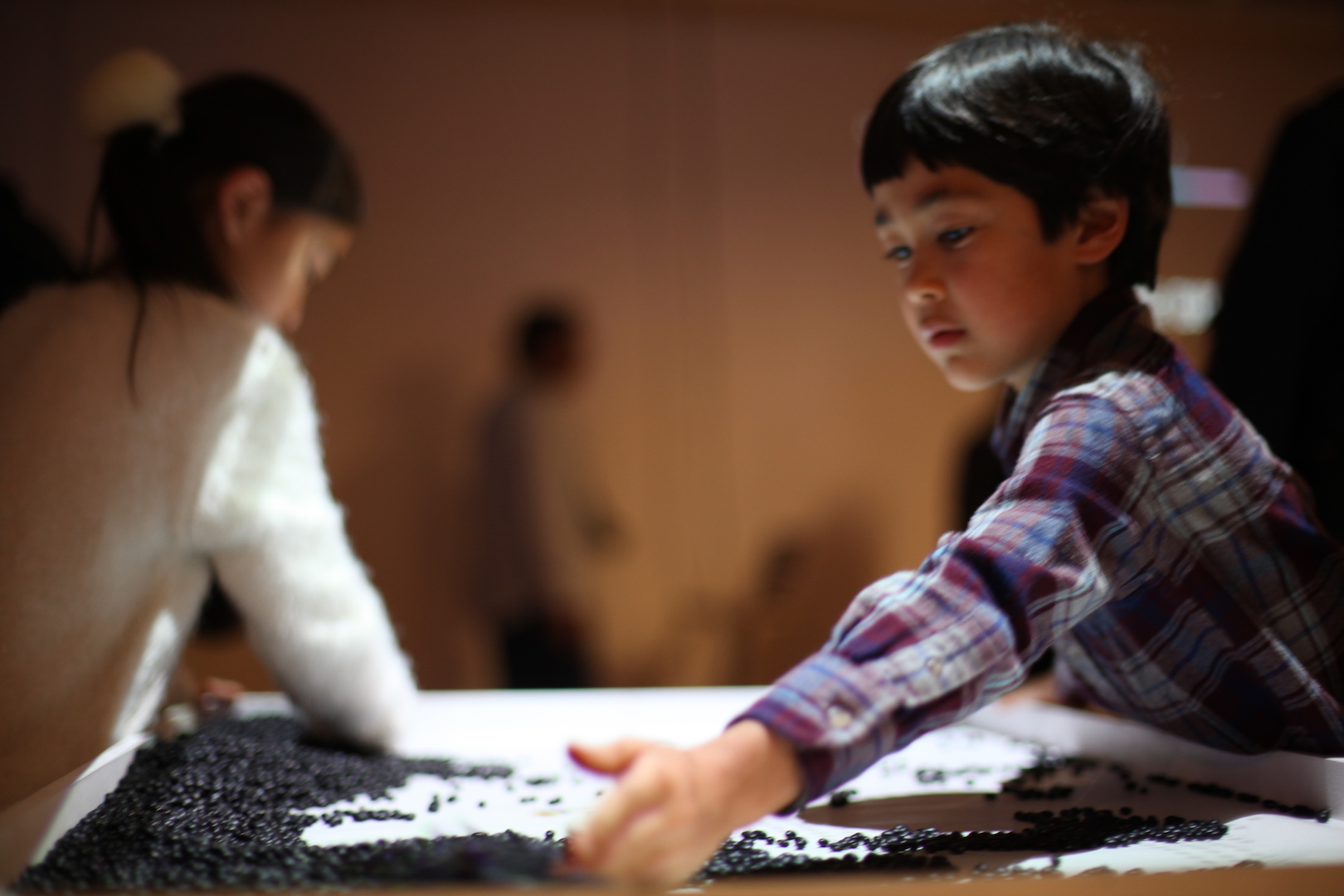 a boy and girl moving around dried black beans
