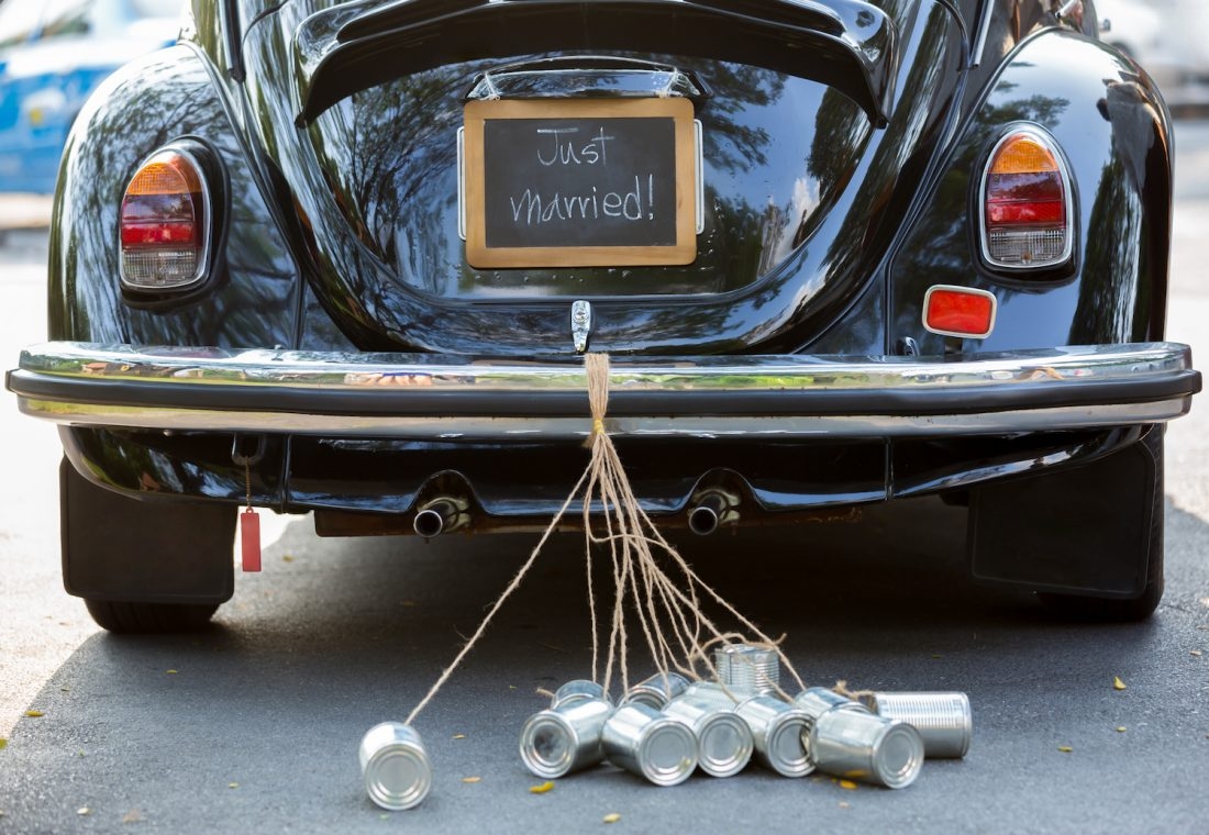 Image of a car with cans attached which reads "Just Married"