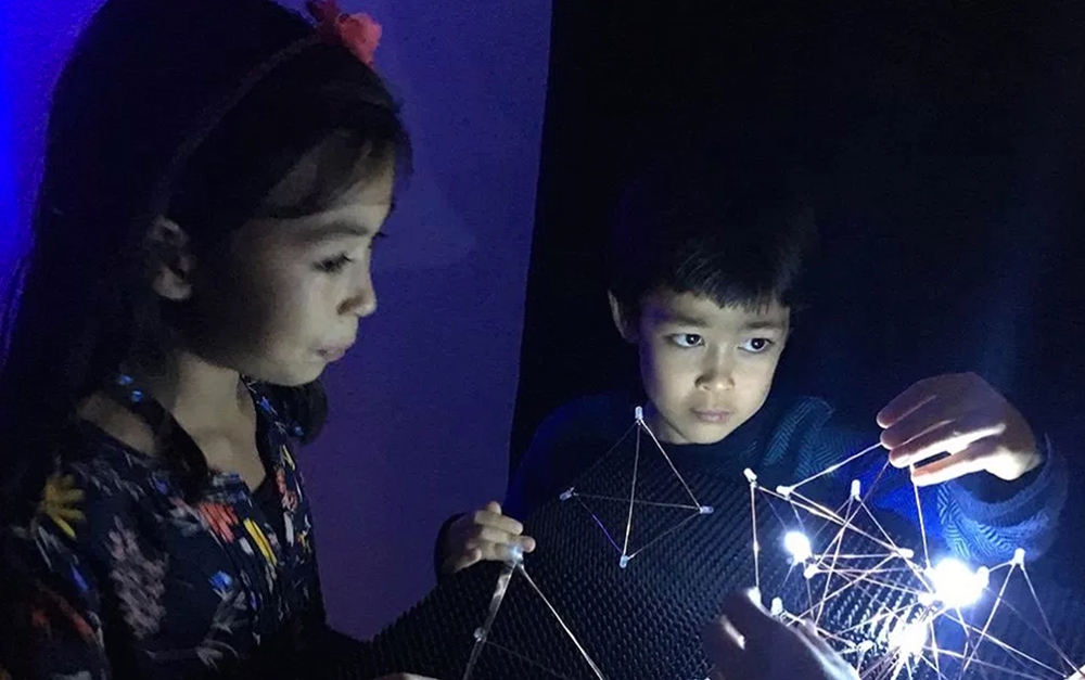 Two kids playing with geometric shapes and LED lights