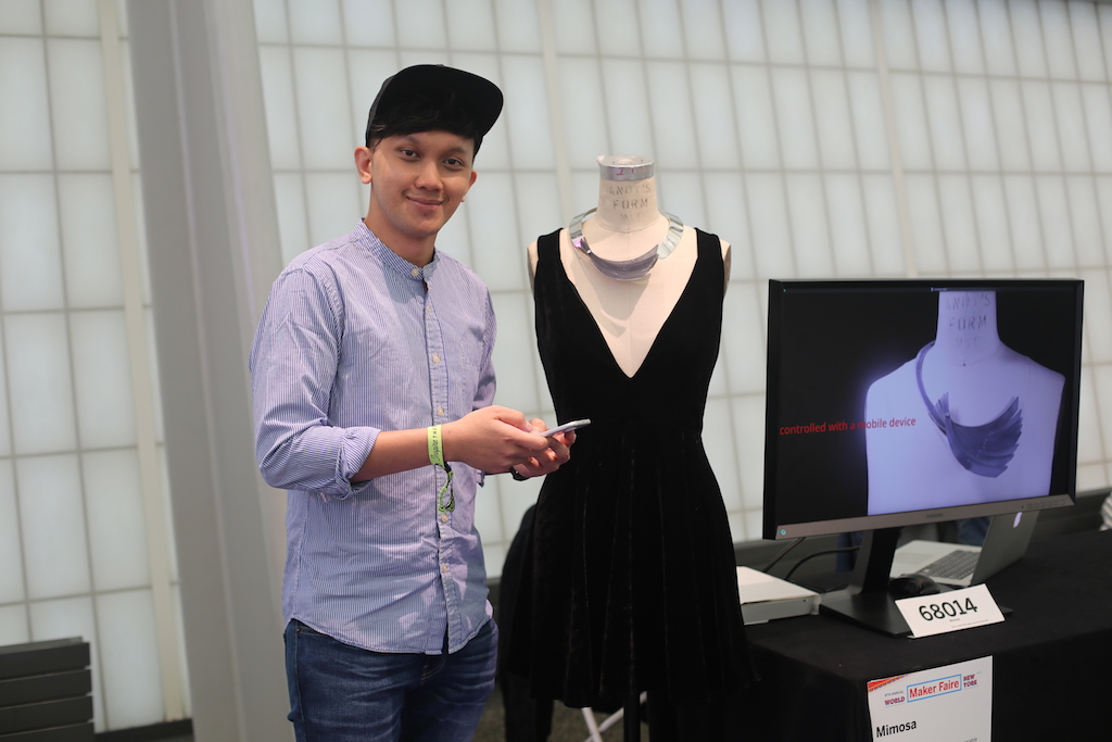 Student poses with project of dress on a mannequin