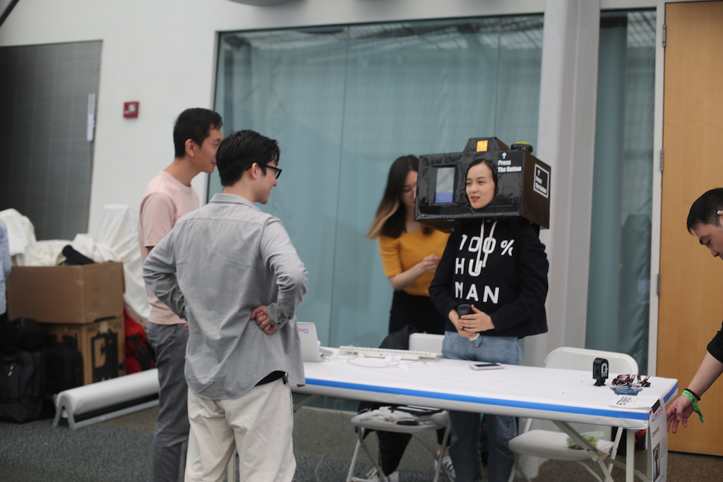 Student explains project to visitors while wearing large camera on head