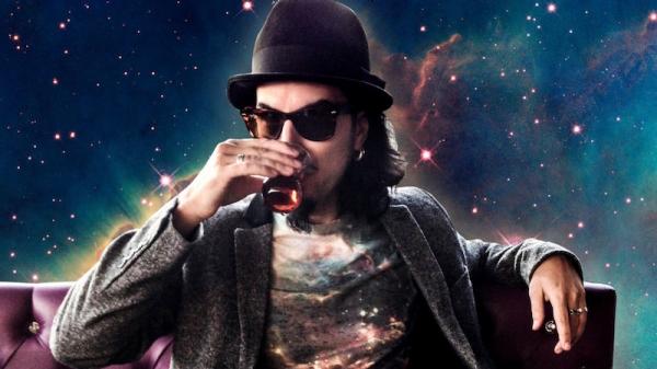 Image of Memo Akten, sipping a drink on a leather couch in outer space