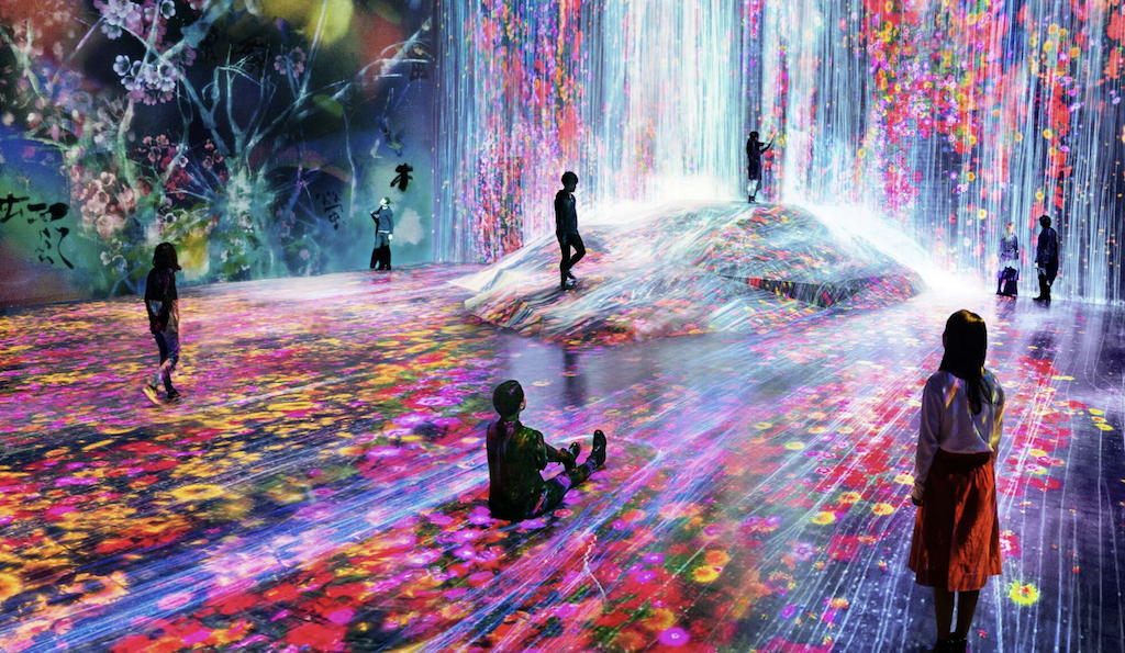 Image of a group of people in a large space with projects on the floor, ceiling, and walls creating an immersive space