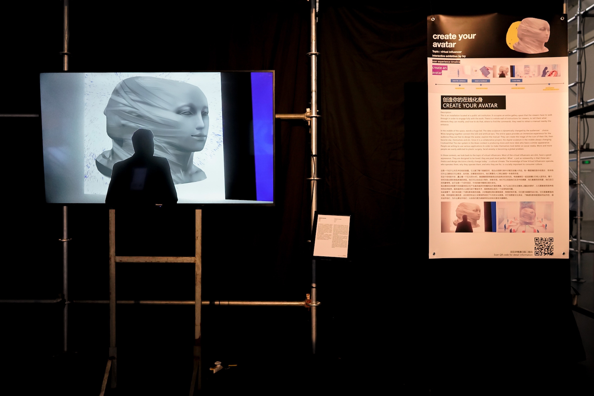 A large screen displays a 3D figure of a two sided head. Next to it is a placard displaying information about the work in Chinese and English with the words "CREATE YOUR AVATAR"