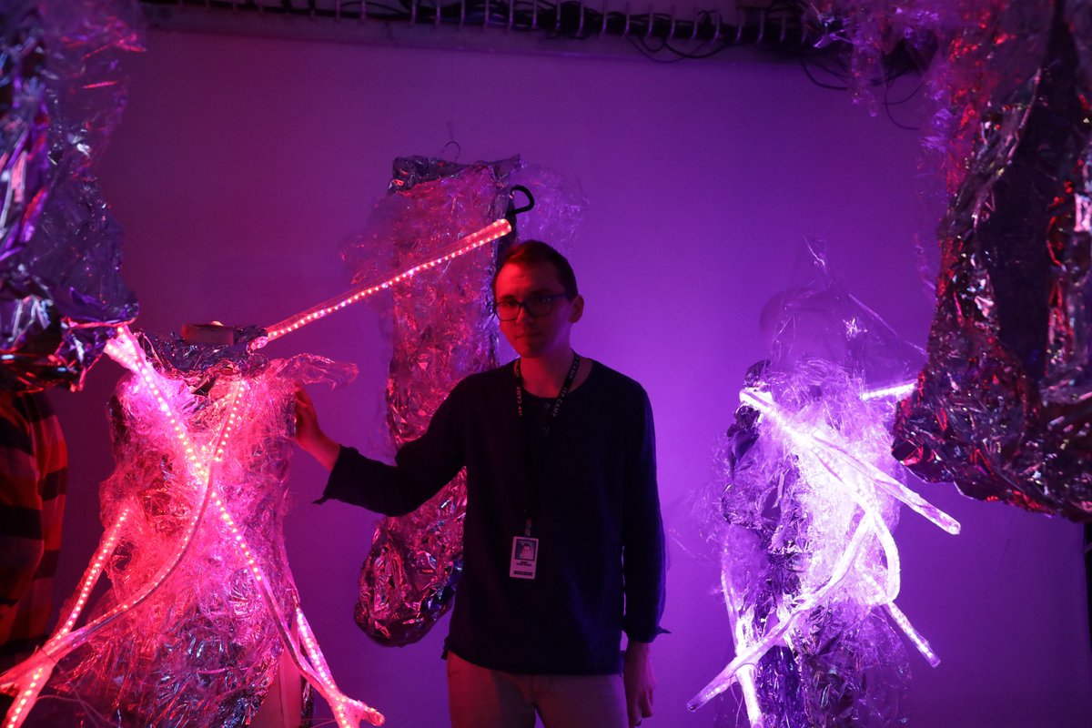 pink and purple color hues with a man in the middle wearing glasses