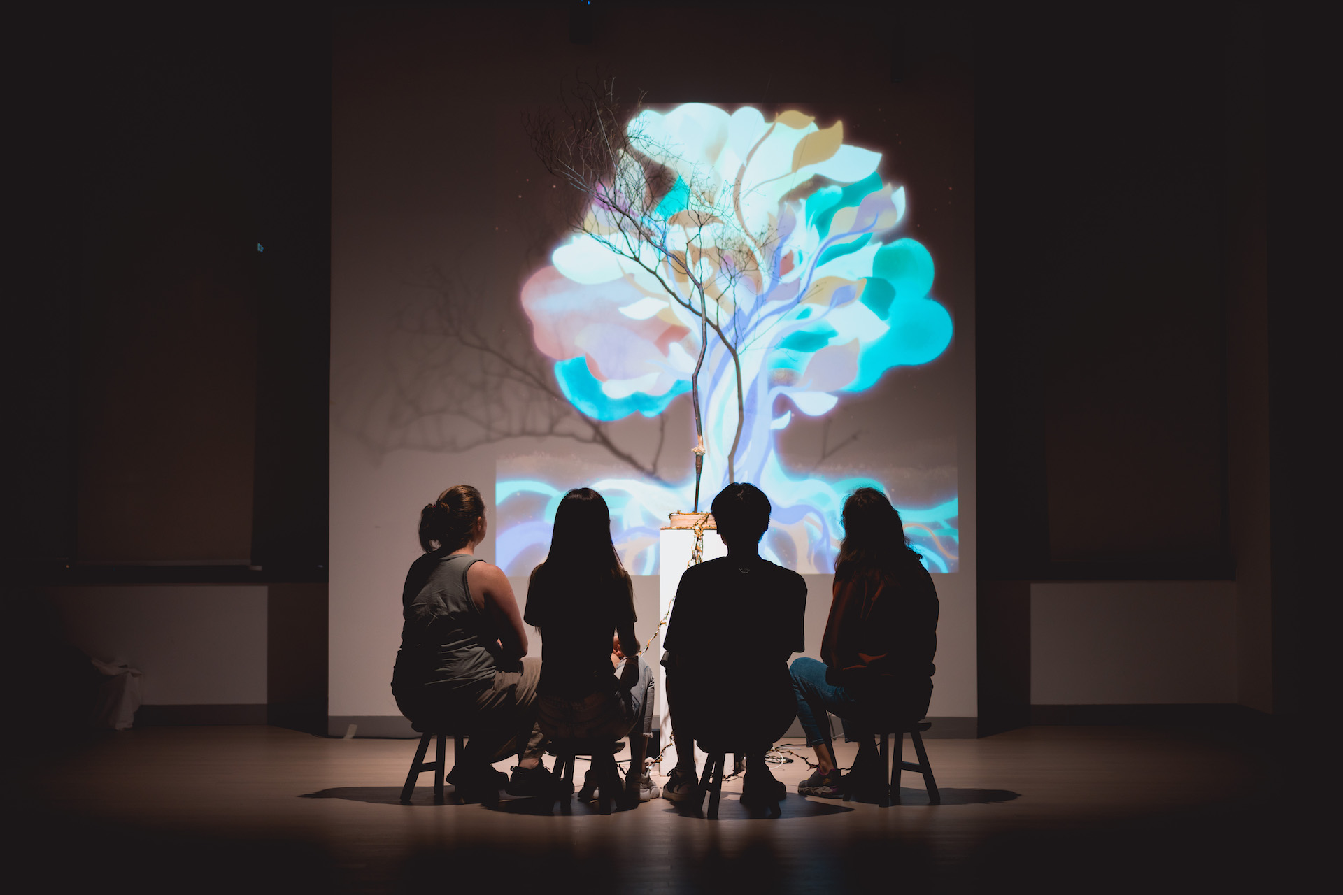 People looking at a projection of a colorful tree