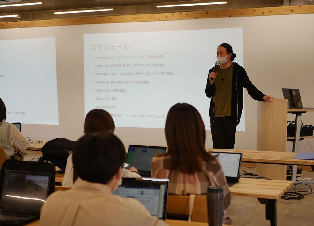 Tetsu giving a lecture in front of a powerpoint