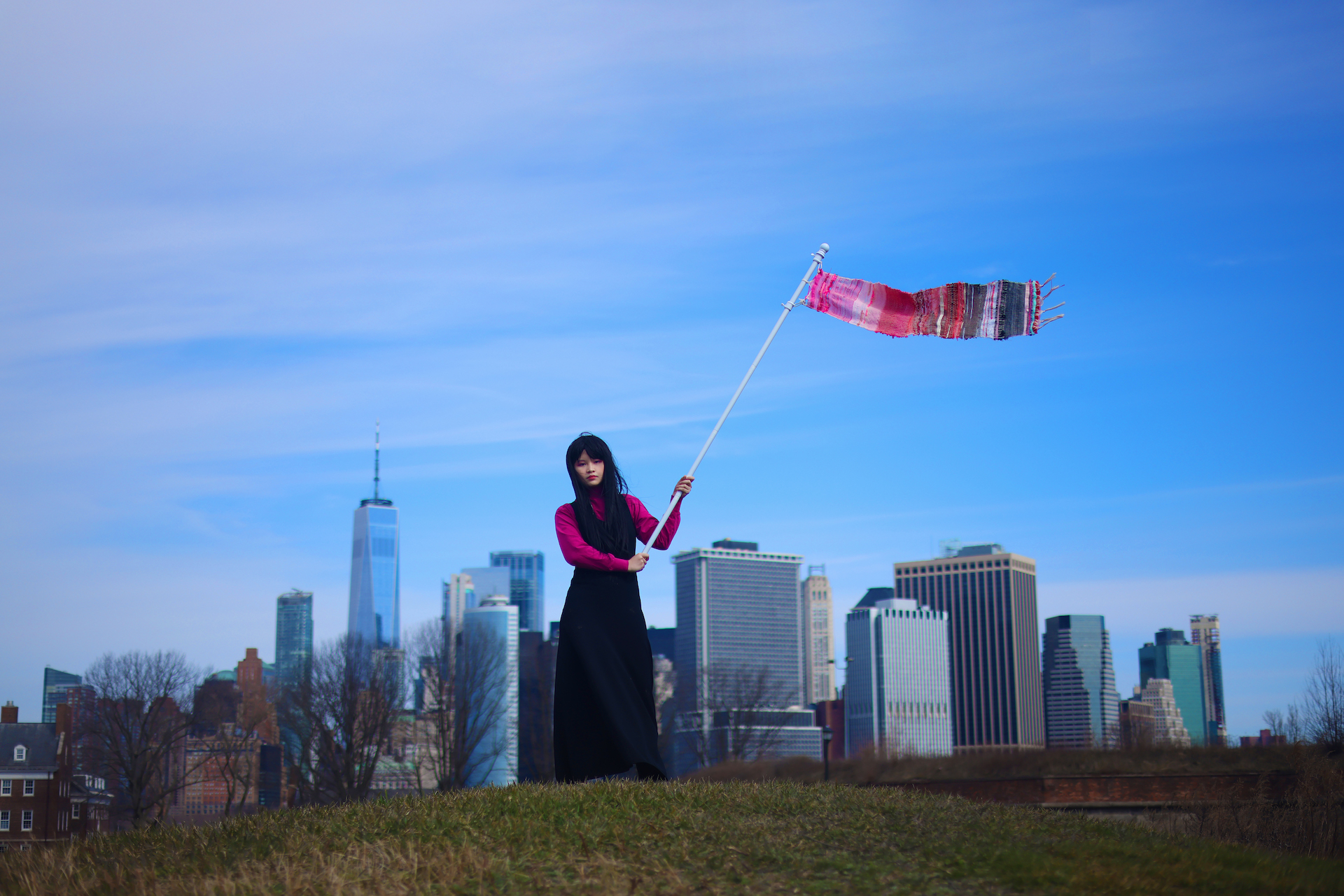 Mingyue Chen waving a flag with the new york skyline in the background