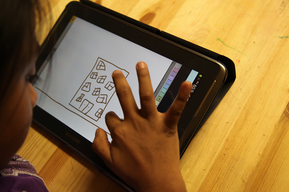 an ipad app where a child is drawing a house on it