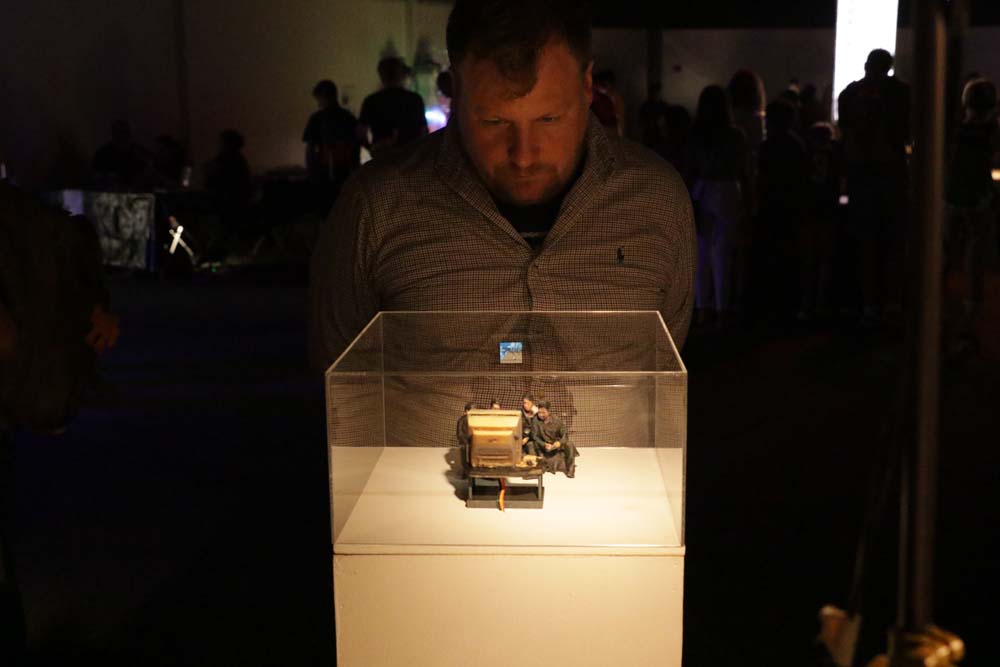 A man looking at a small sculpture of a group of people watching TV