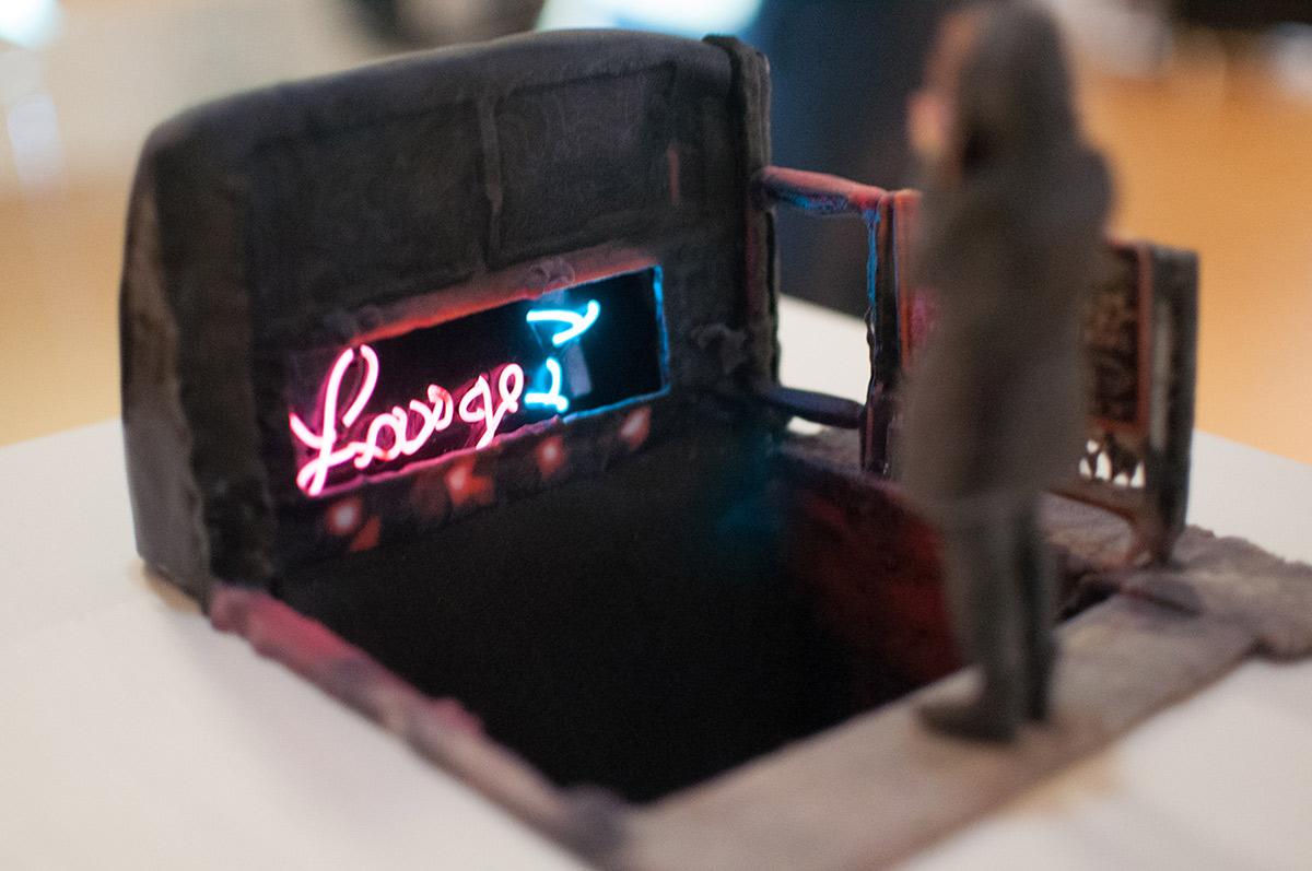 a miniature view of a person looking at a lounge sign that is lit up