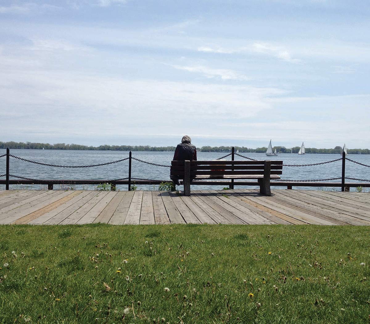 a person sitting on a bench looking out onto a lake