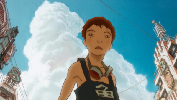Film still: low angle on a boy standing with the blue sky behind him