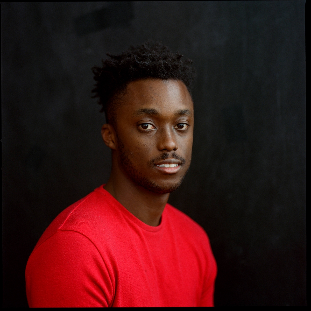 Nile Harris in a red t-shirt against a black background