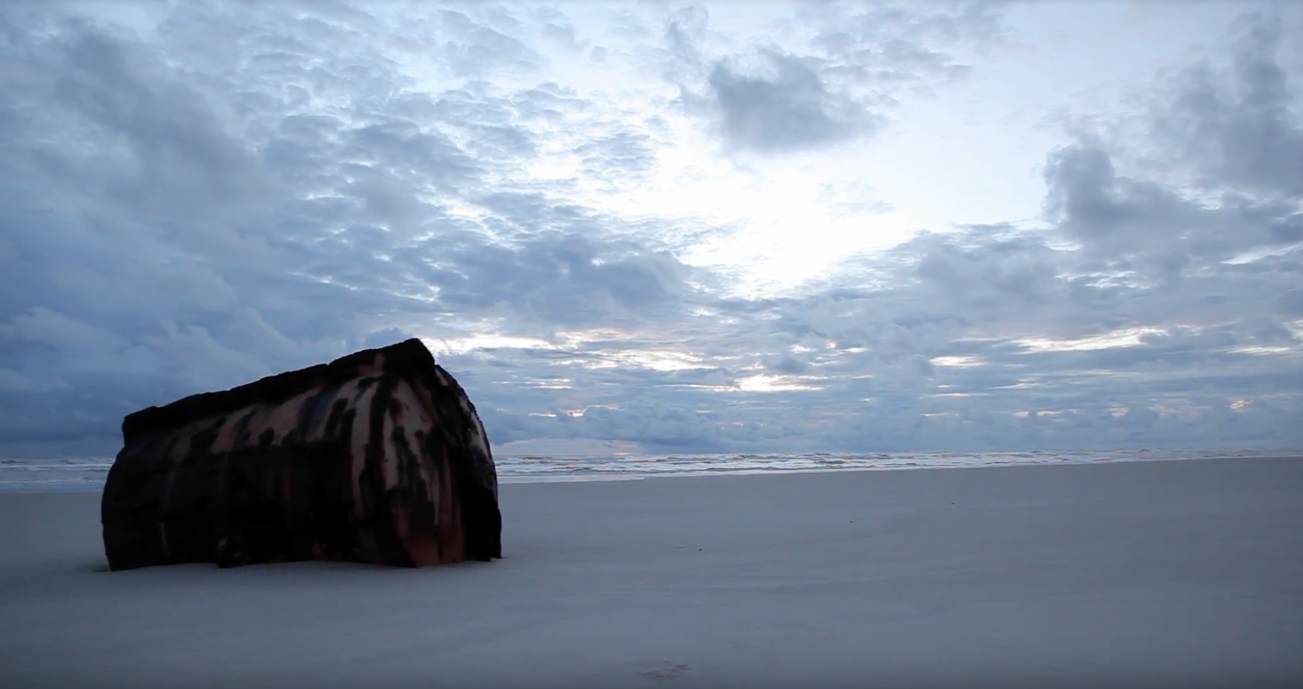 A big boulder sitting on a beach