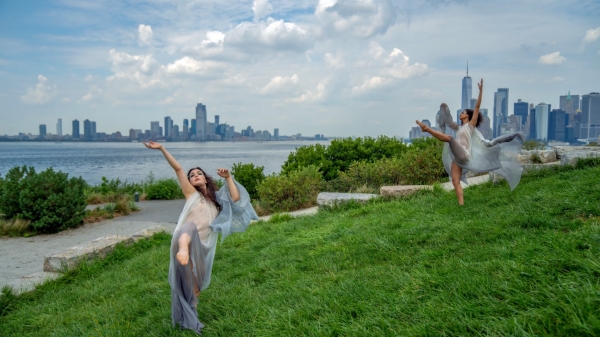 Women dancing with the NYC skyline behind them