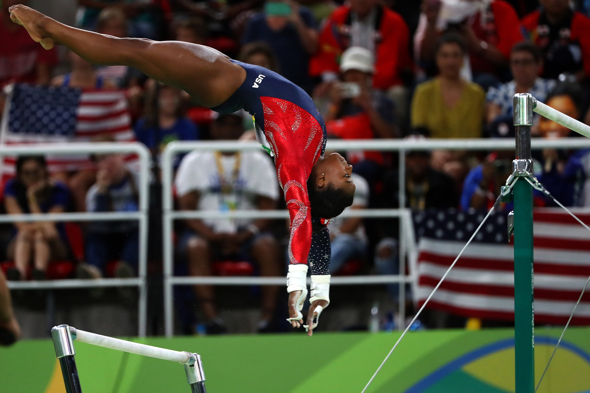 a female gymnast performs on the uneven bars