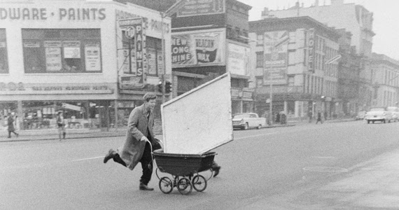 An artist in 1950s New York uses a wheelbarrow to carry his canvases.