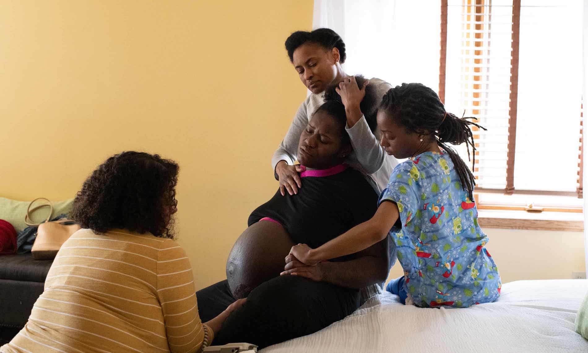 Rebecca Polston, a midwife, watches Em’Mae Alexander labor with the support of her mother, Tulani Alexander and her doula, Lakesha Gordon at Roots Community Birth Center. Alice Proujansky/The Guardian