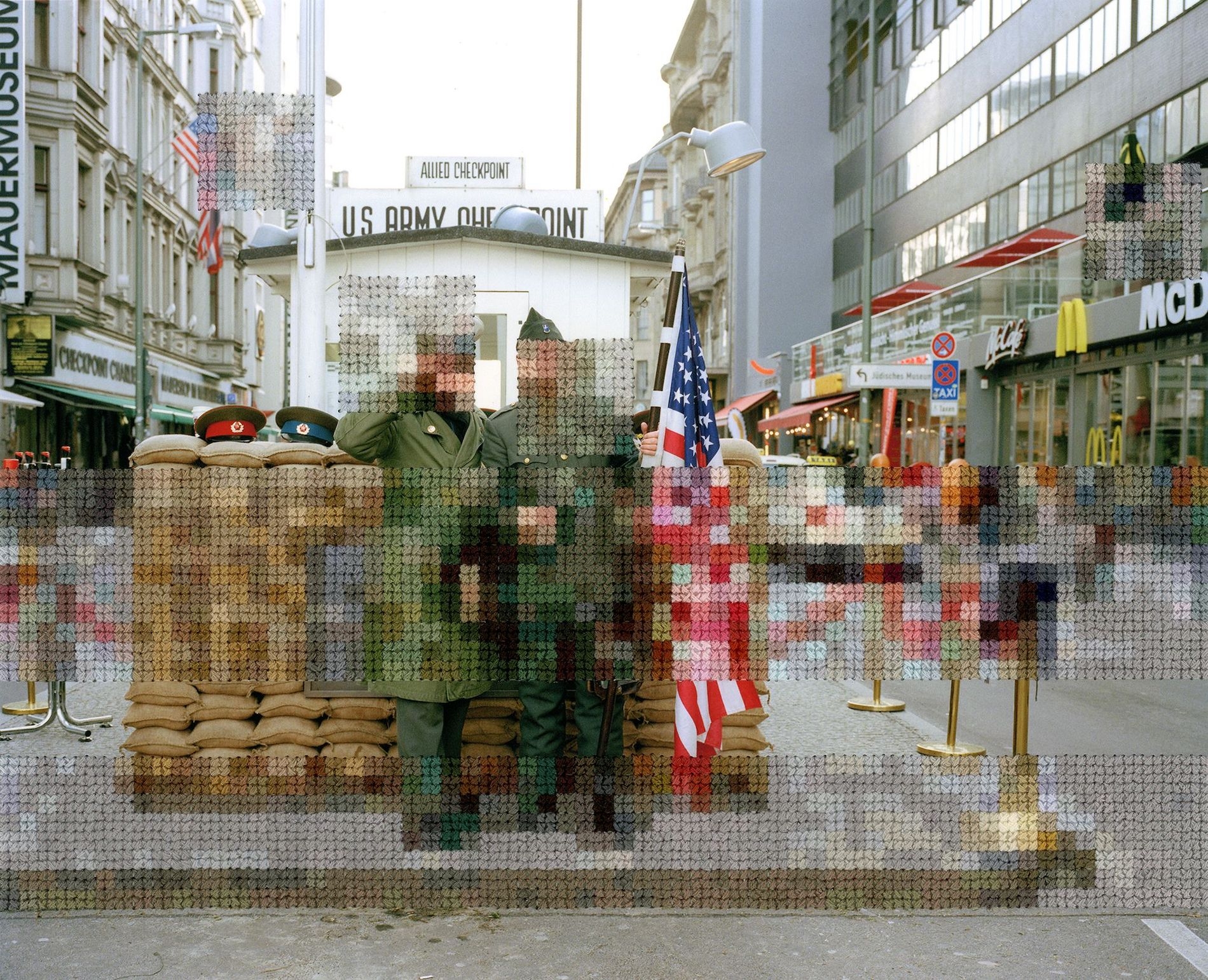Color photo of Berlin military checkpoint with embroidery resembling pixels stitched into parts of the image