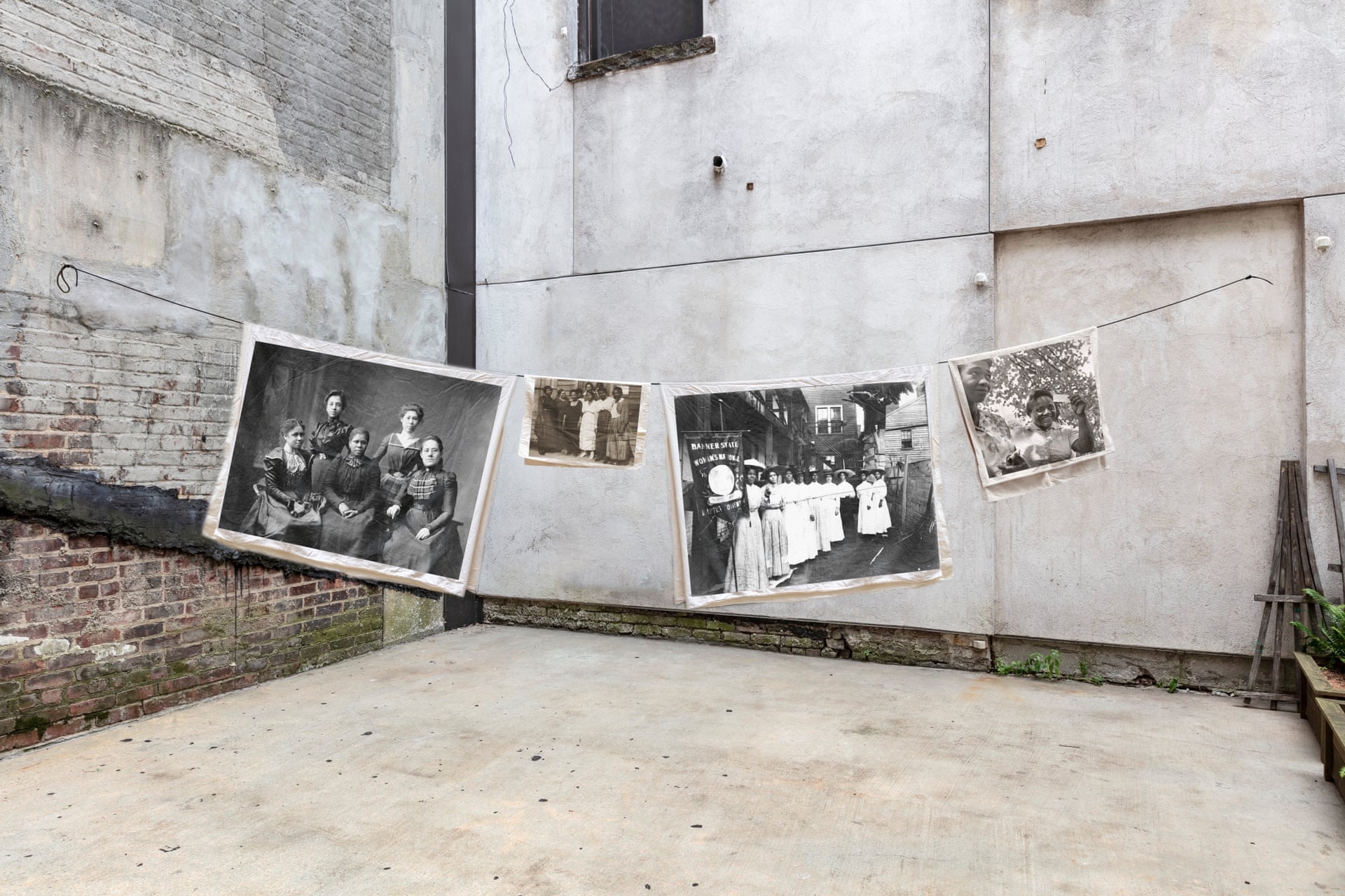 Images of suffragettes hang in a clothesline in a back alley