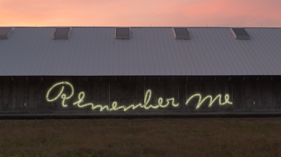 Neon lights that spell out "Remember me" on the side of a barn at sunset