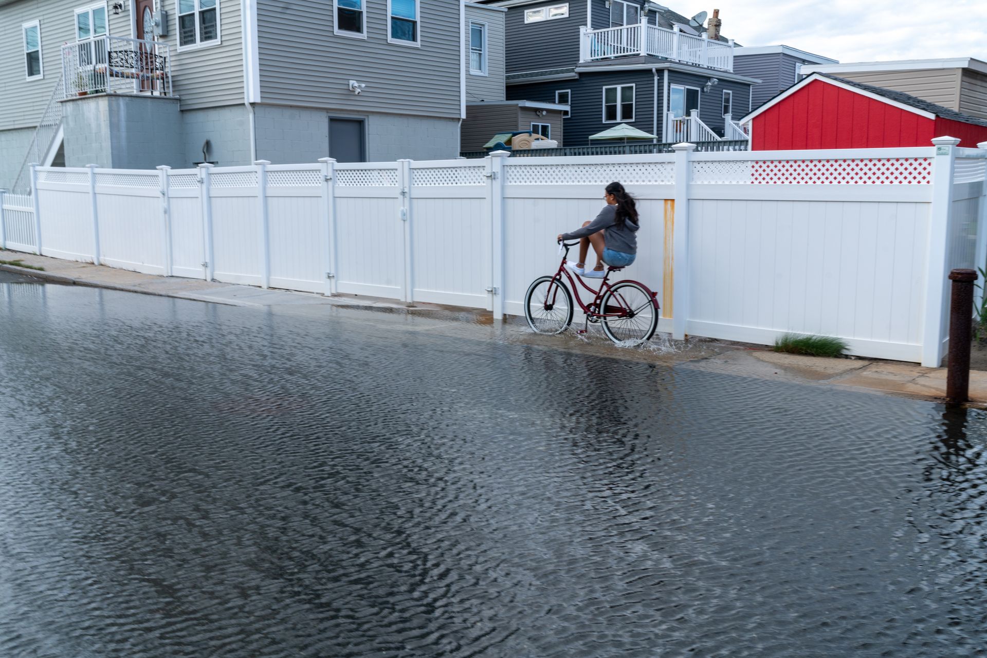 boy on bike rides down flooded street