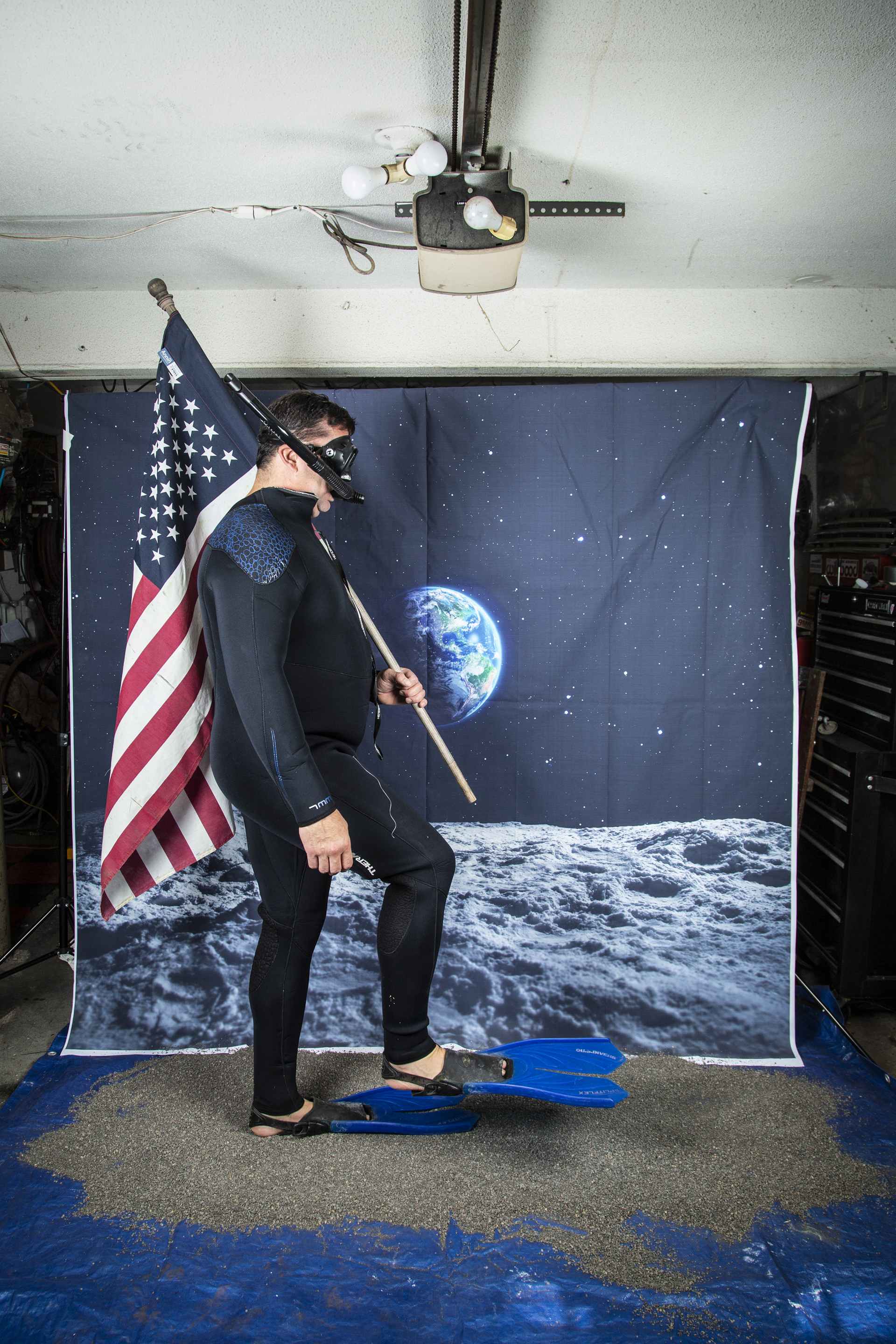 man carrying flag wearing flippers with earthrise image behind him