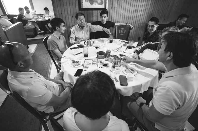 black and white photo of people gathered around a round dining table