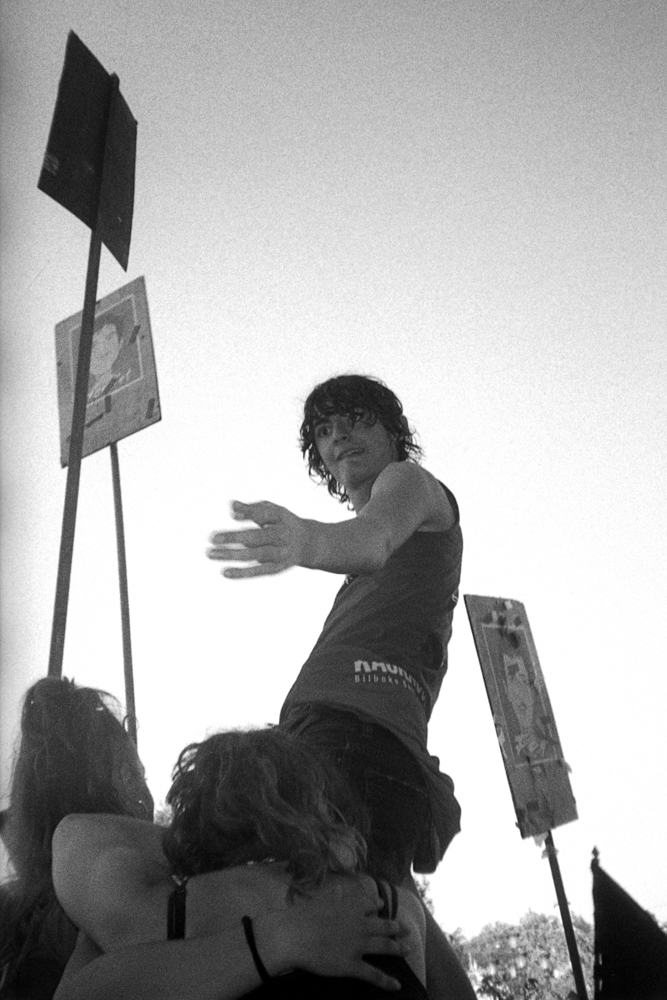 black and white photo of protestors raising one of the group with signs