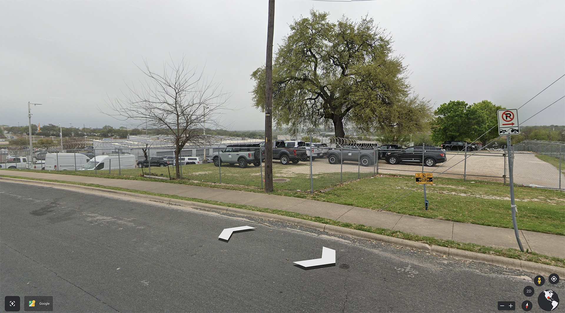 landscape image of a parking lots with cars, trucks, and a tree in the distance. 