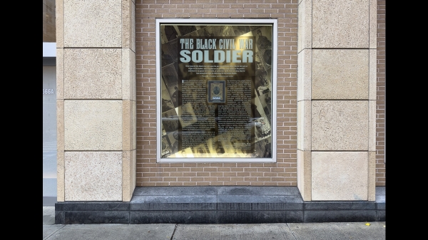 A photograph of a window containing other photographs and text from the book The Black Civil War Soldier by Dr. Deborah Willis