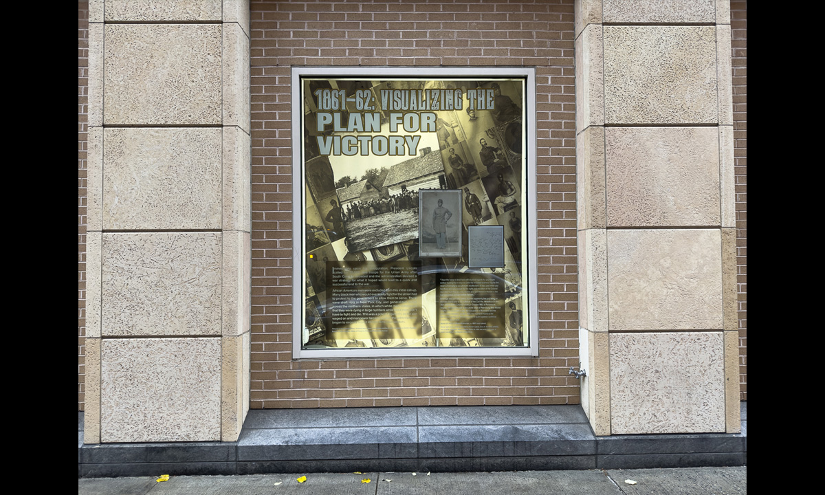 A photograph of a window containing other photographs and text from the book The Black Civil War Soldier by Dr. Deborah Willis