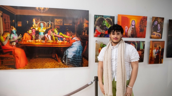 Carlos standing in a gallery in front of own artwork