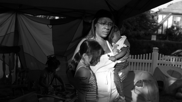 A photo of a daycare provider holding her granddaughter and a second child at Dee's Tots Childcare in New Rochelle New York.