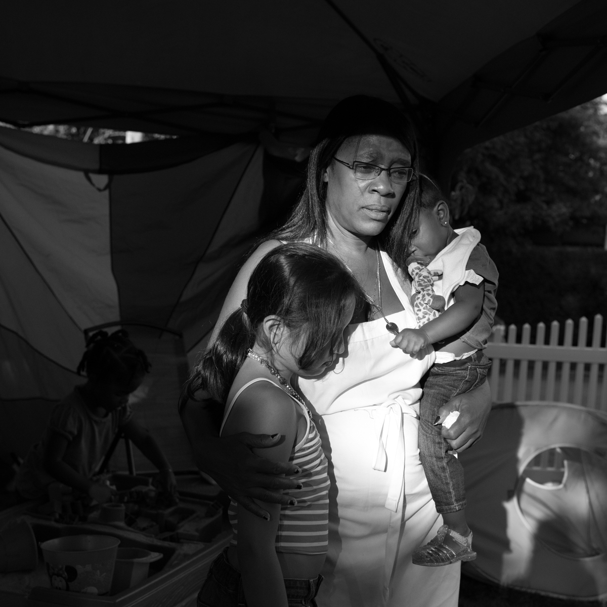 A photo of a daycare provider holding her granddaughter and a second child at Dee's Tots Childcare in New Rochelle New York.