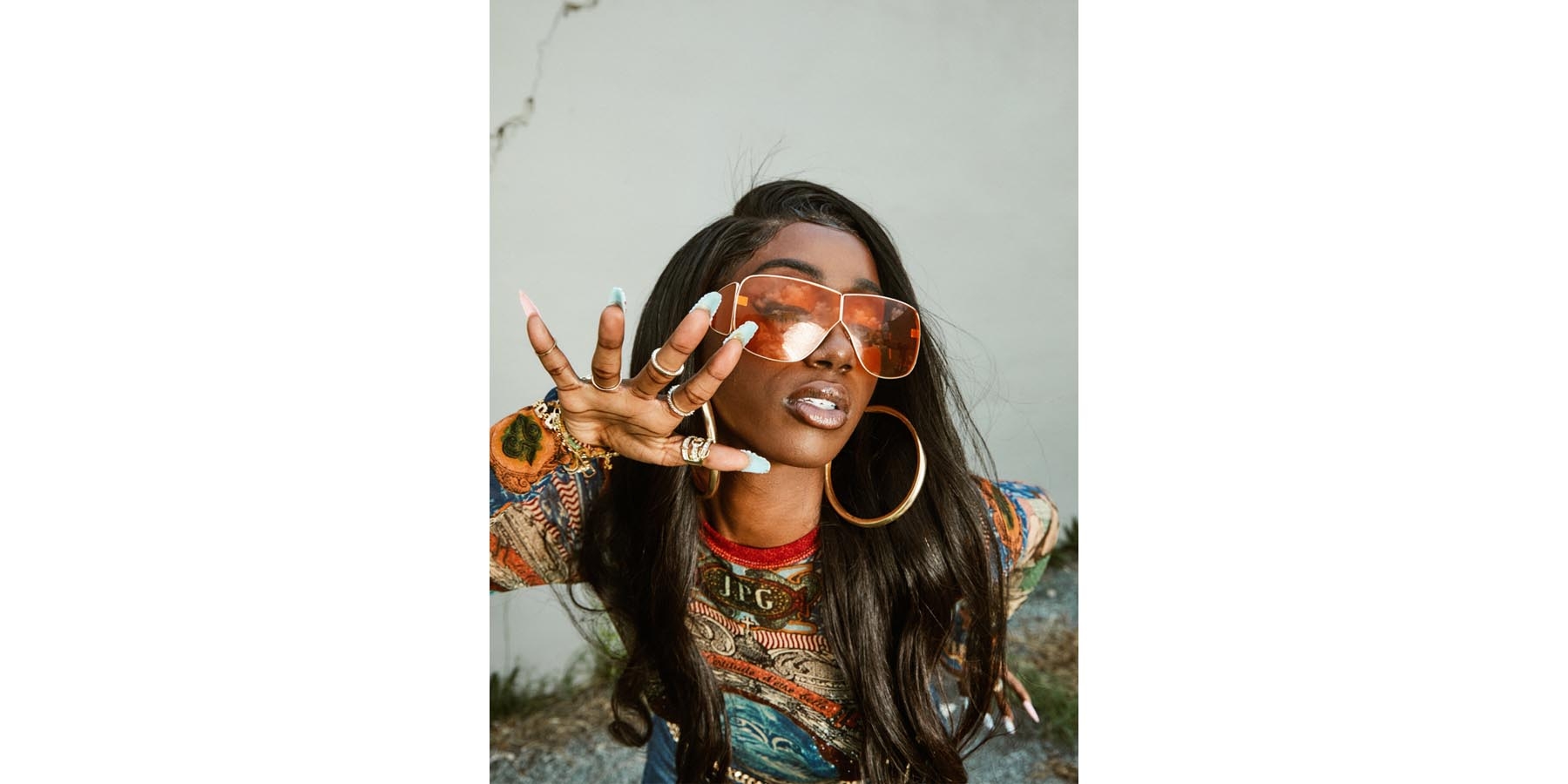 Flo Milli poses for the camera with distinctibve sunglasses and fingernails