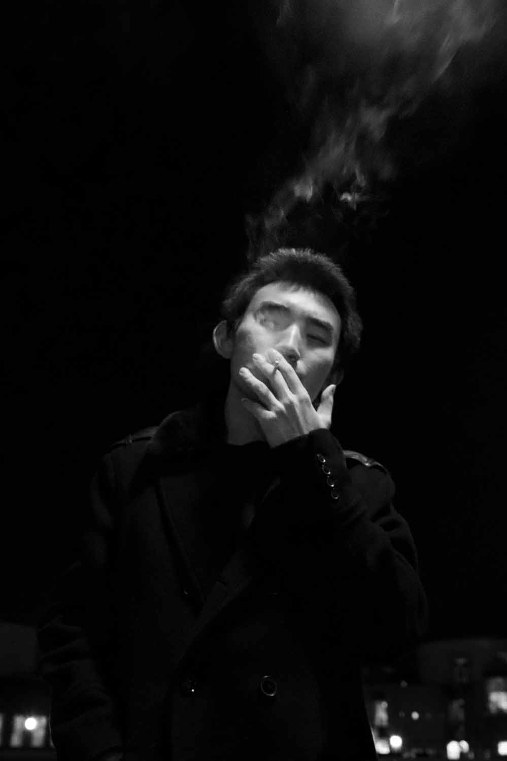 man smoking cigarette, bw photo with dark background