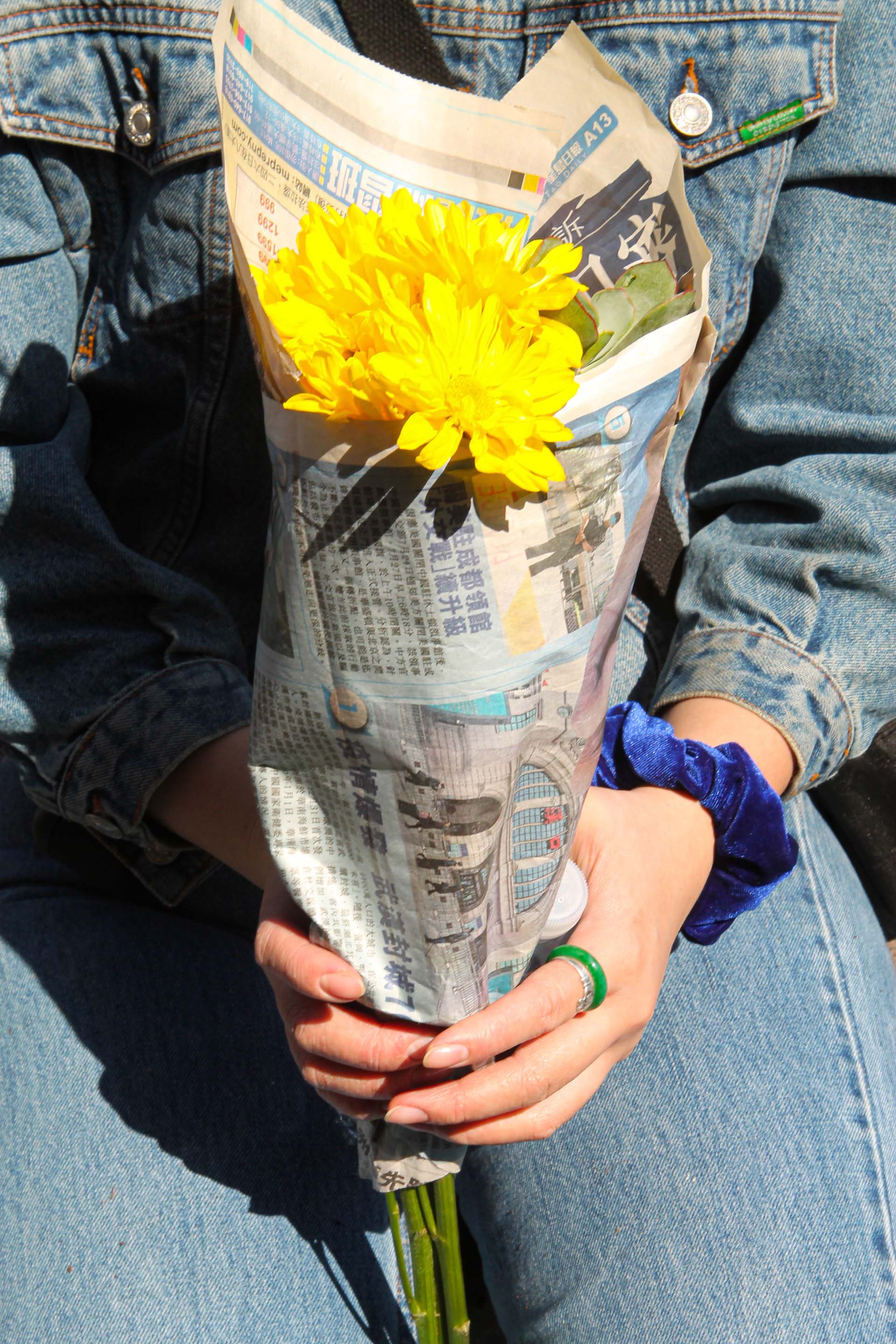 protestor carrying yellow flowers wrapped in newspaper