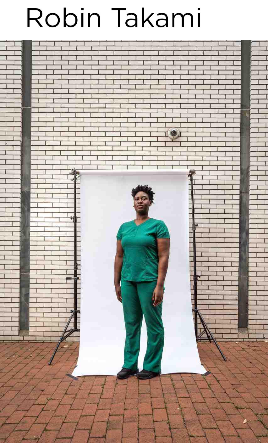 woman in medical scrubs outdoors in front of white paper background with stand