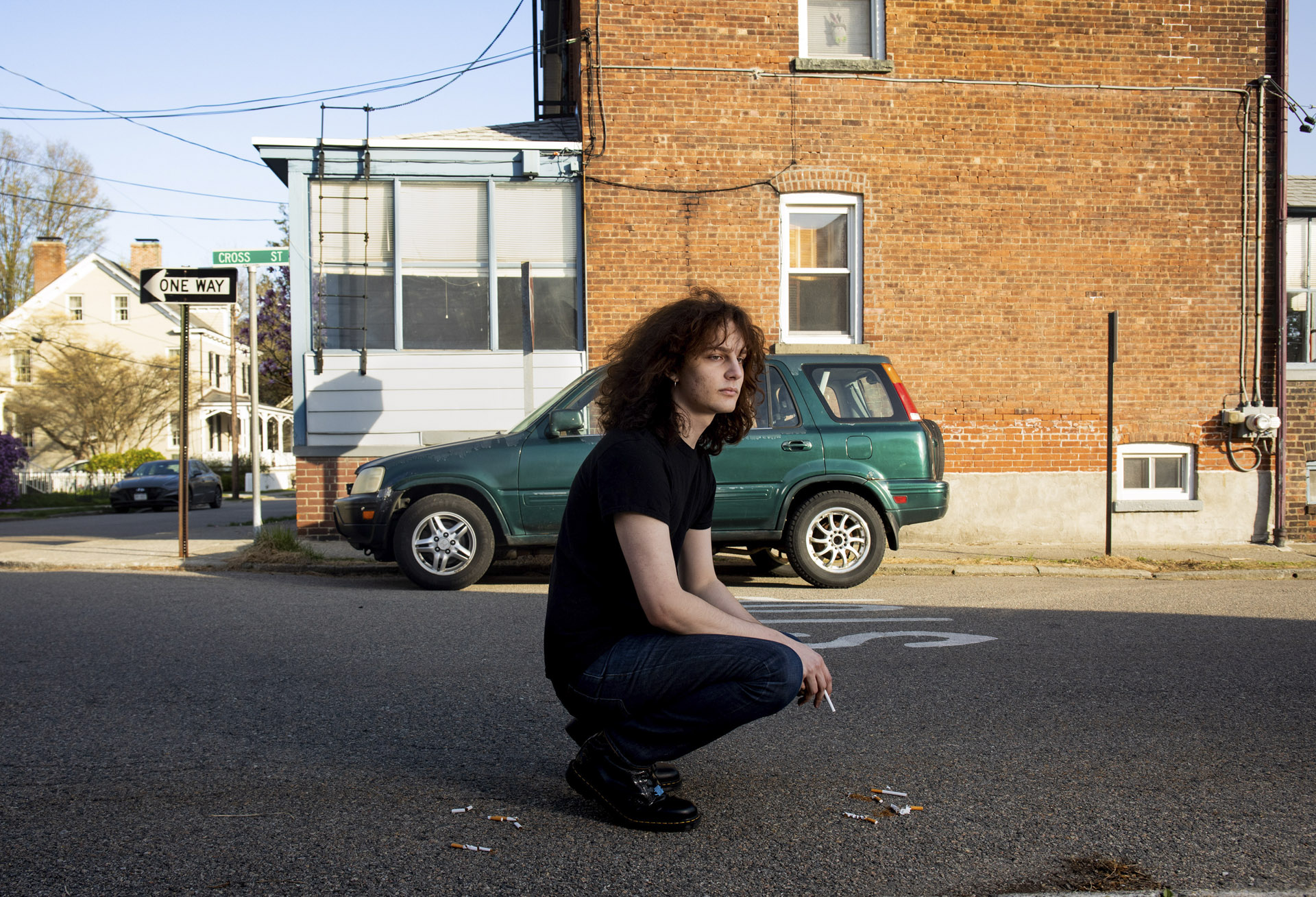 outdoor portrait of a person seating with car in background