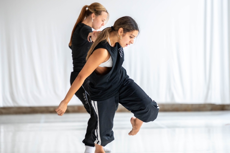 Two dancers moving during a training session in a dance studio
