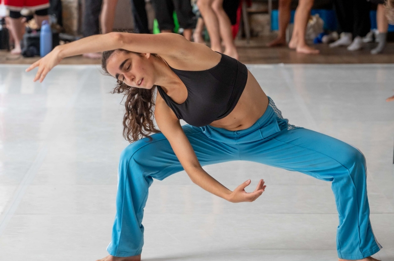 A dancer stretching over their head in a position during a training session in a dance studio